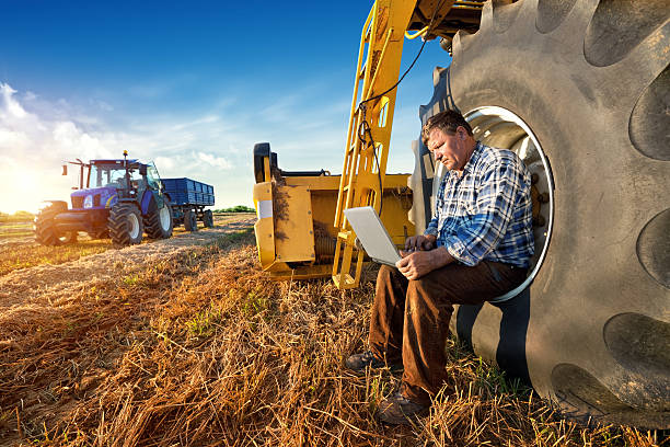 Farmer sitting on flat tire of large tractor.
